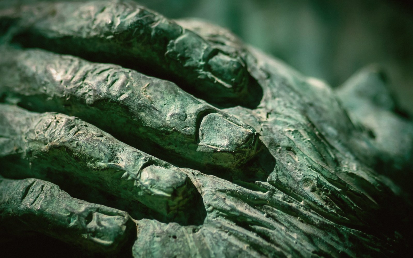 Bronze surface detail at close range, raking light across ornament