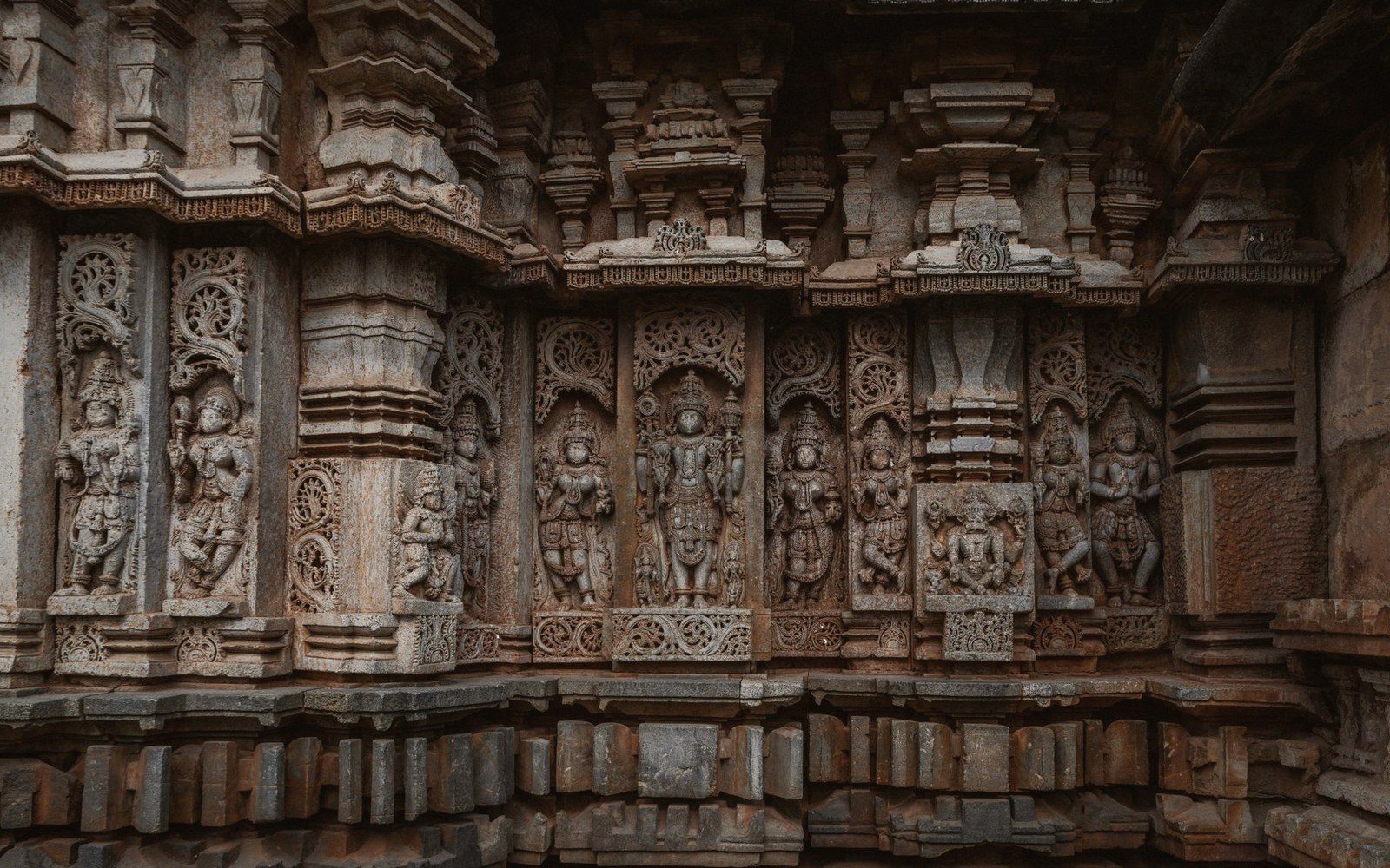 Row of intricately carved deity figures on a stone temple wall's outer frieze
