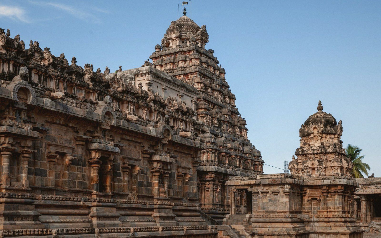 Tiered pyramidal tower of a stone temple with intricately carved tiers rising against a clear sky